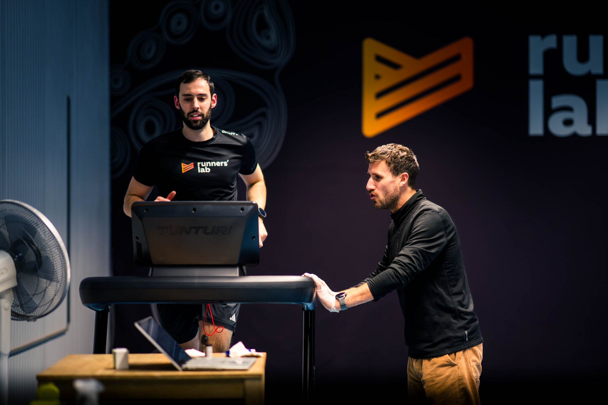 Running coach analyzing athlete performance on treadmill